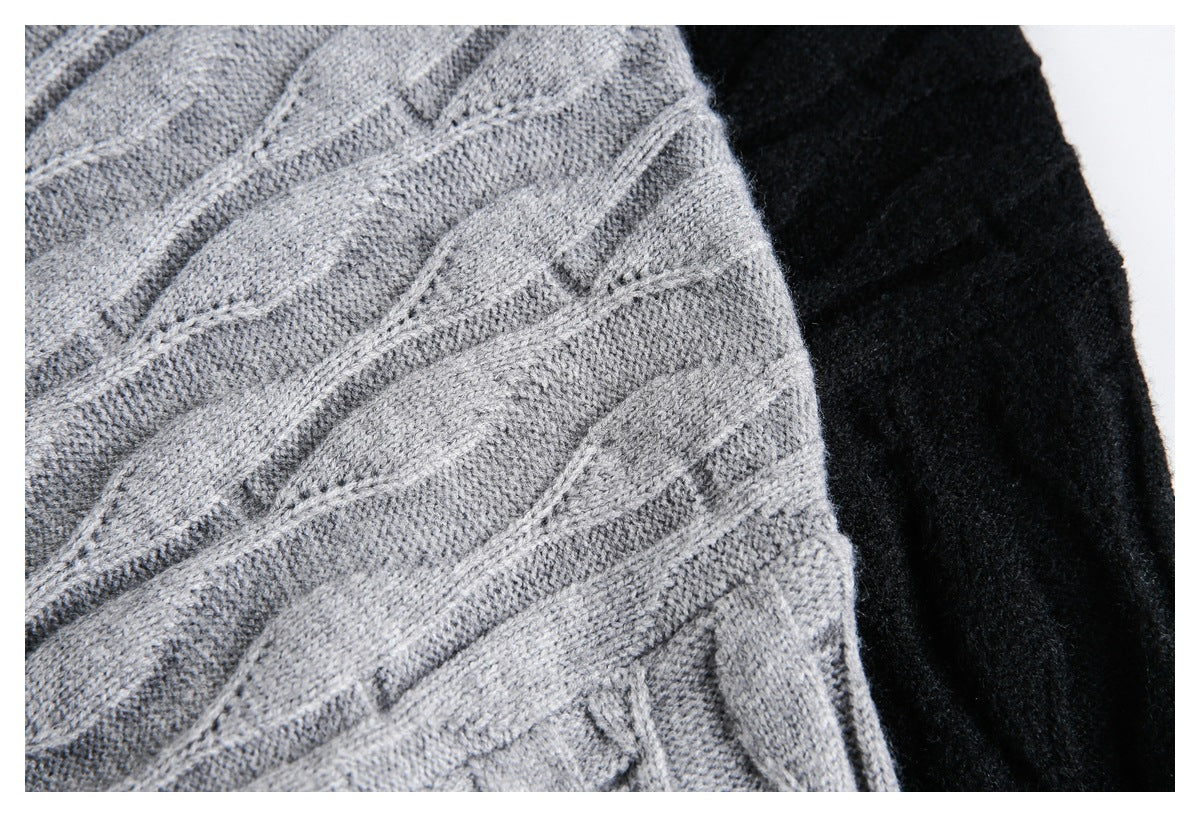 Close-up showing the raised cable-knit texture of a gray sweater beside black knit fabric.