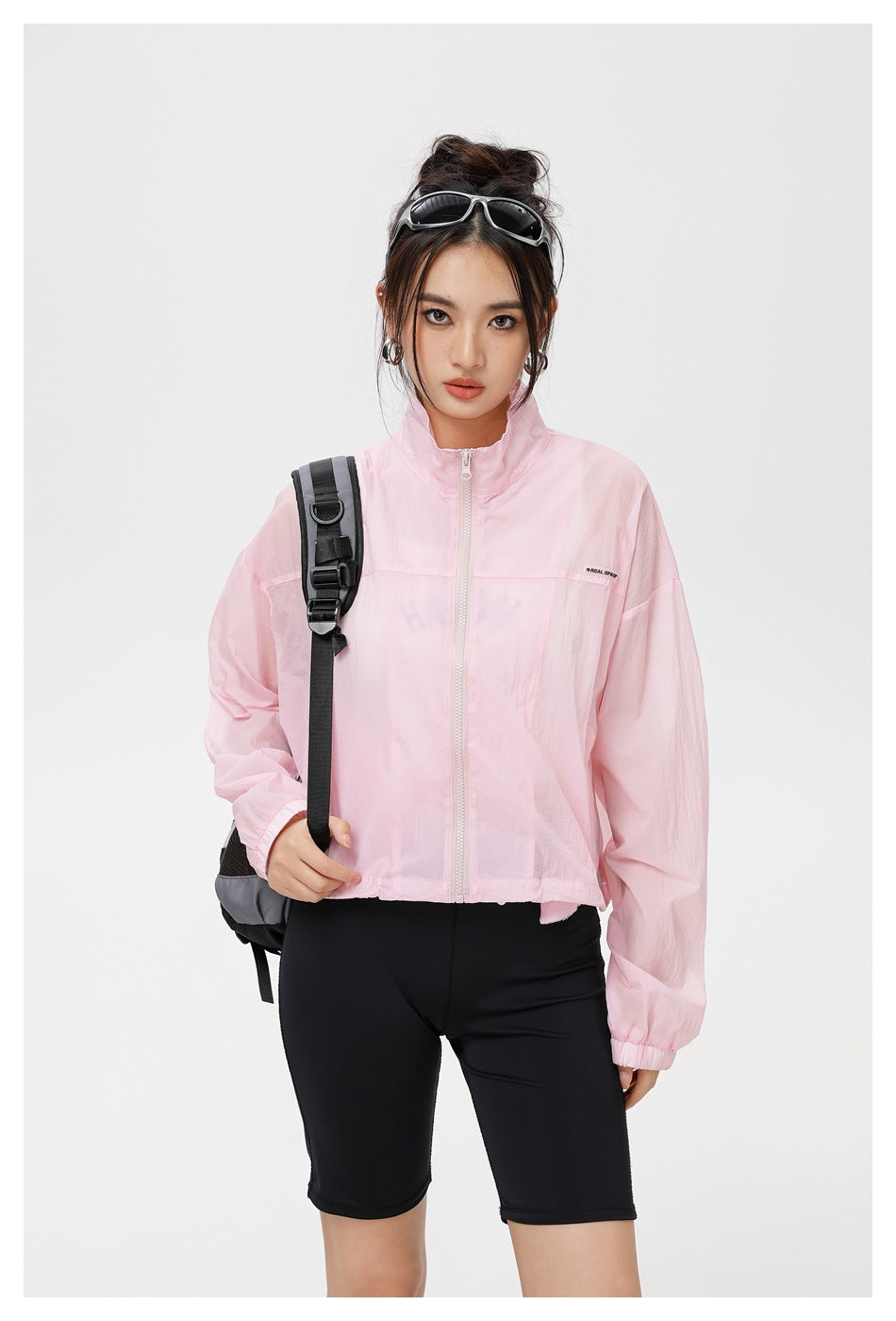 Closer view of a model wearing a light pink zip-front jacket with elastic cuffs and a stand collar.