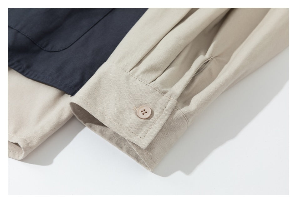 Close-up of a beige sleeve cuff with a button beside dark navy garment fabric.