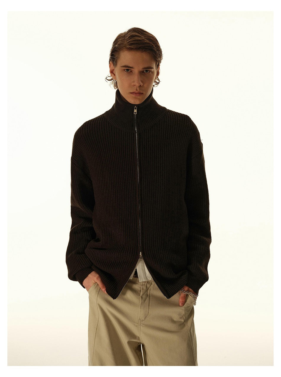 Model wearing a dark ribbed sweater zipped to its high stand collar.