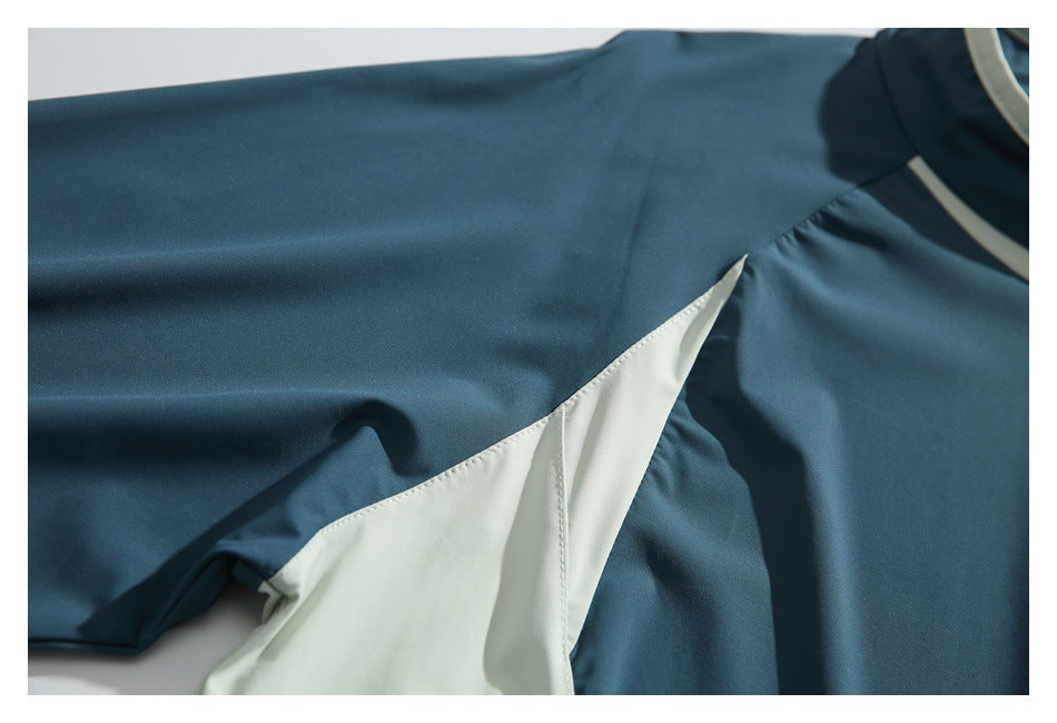 Close-up of a teal sleeve and pale mint triangular color-block panel with visible stitching.