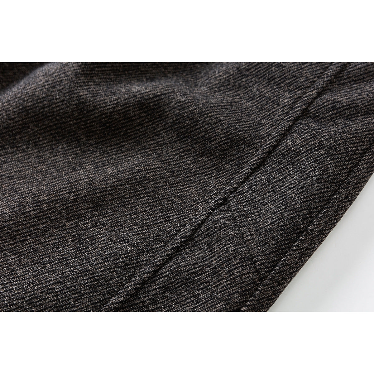 Close-up of dark brown heathered trouser fabric with a diagonal seam.
