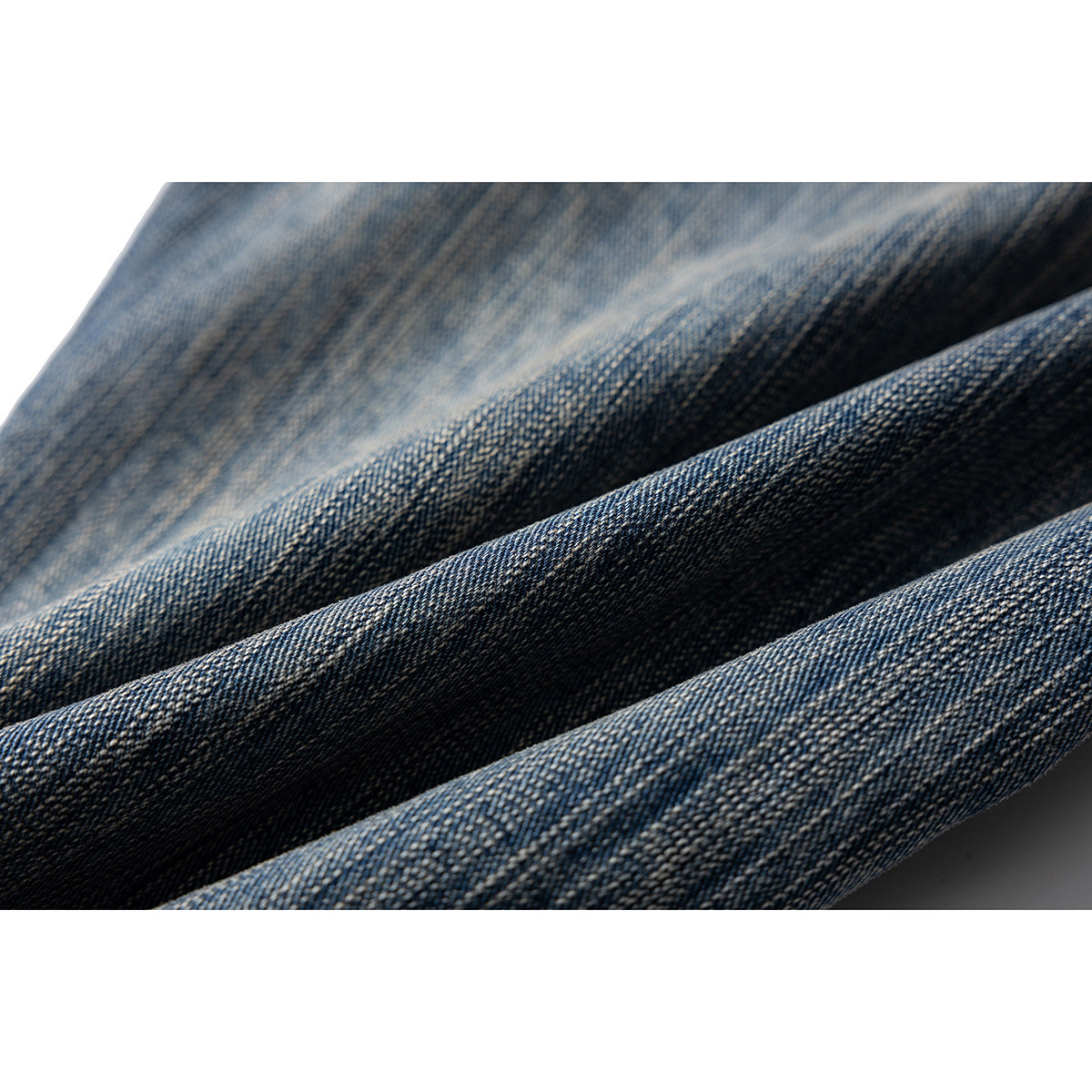Extreme close-up of textured blue denim with faded areas and diagonal folds.