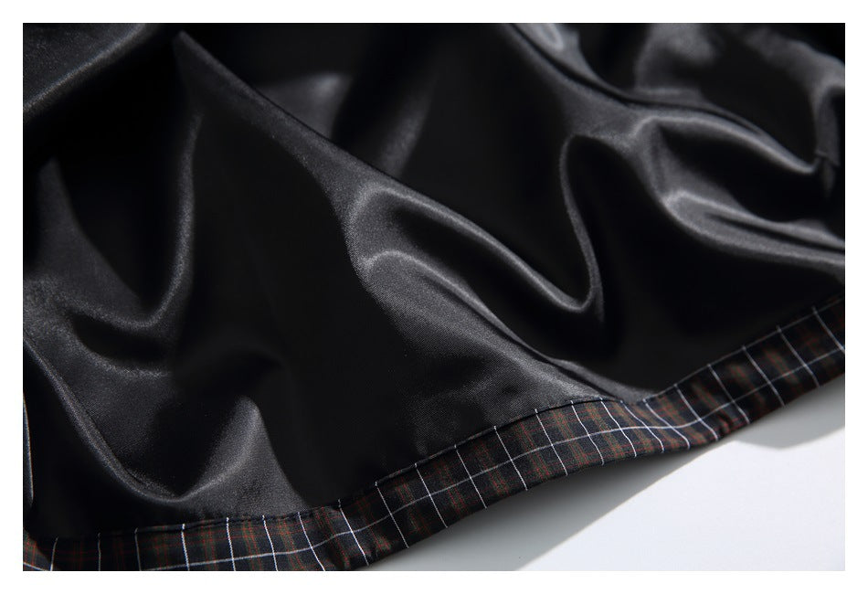 Close-up of smooth black lining joined to the dark plaid garment fabric at the hem.