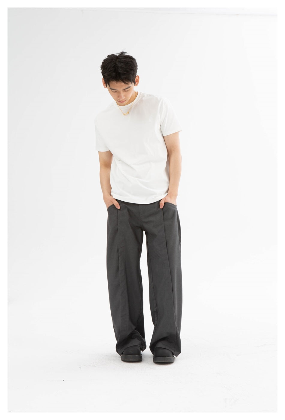 Front view of a model wearing loose charcoal-gray trousers with a white T-shirt.