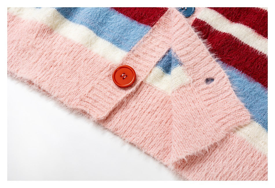 Close-up of a fuzzy pink cardigan placket with a red button and broad red, cream, and blue stripes.