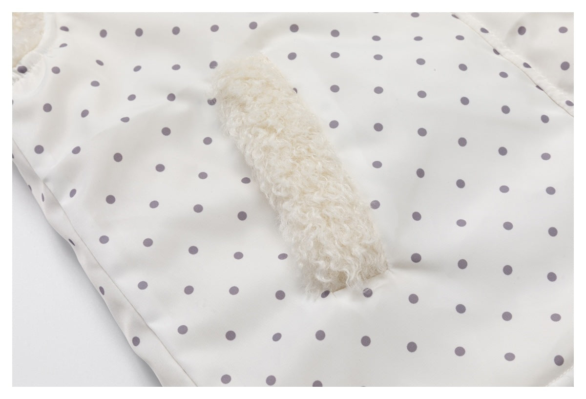 Close-up of a fluffy cream pocket on an ivory jacket with gray polka dots.