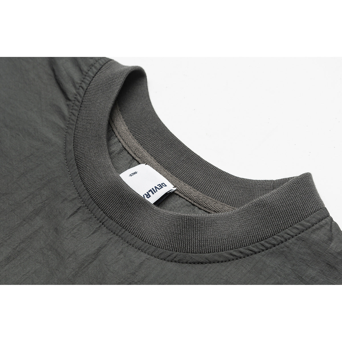 Close-up of a charcoal-gray ribbed crew neckline with a sewn-in white label.