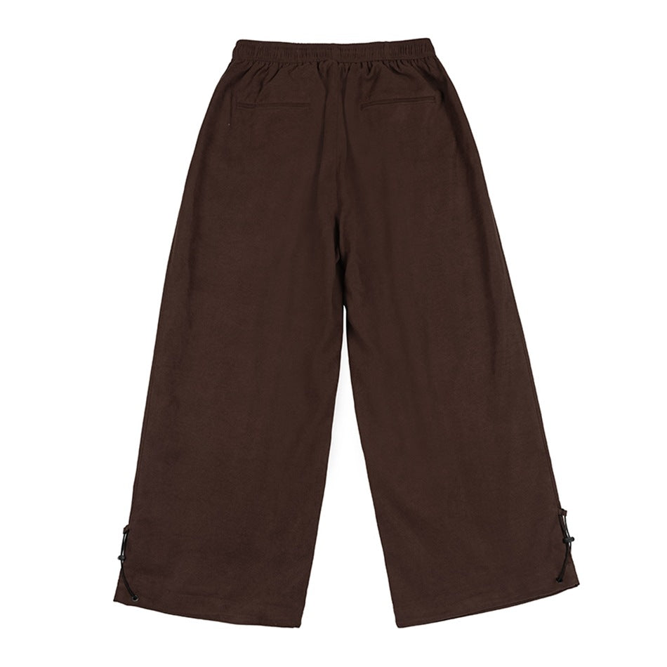 Back view of dark brown wide-leg pants with an elastic waist, two rear pockets, and adjustable ankle cords.