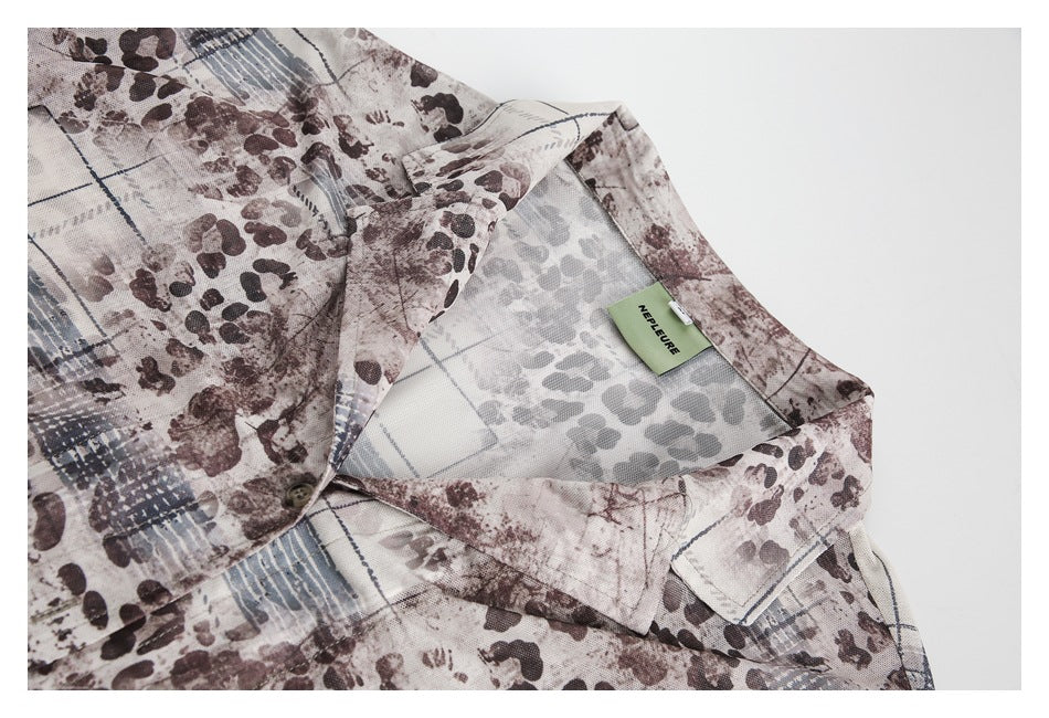 Collared shirt detail in an abstract brown, gray, and blue print, with a small green neck label.