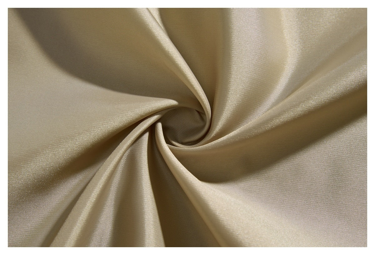 Close-up of pale beige, subtly lustrous fabric gathered into a spiral of folds.