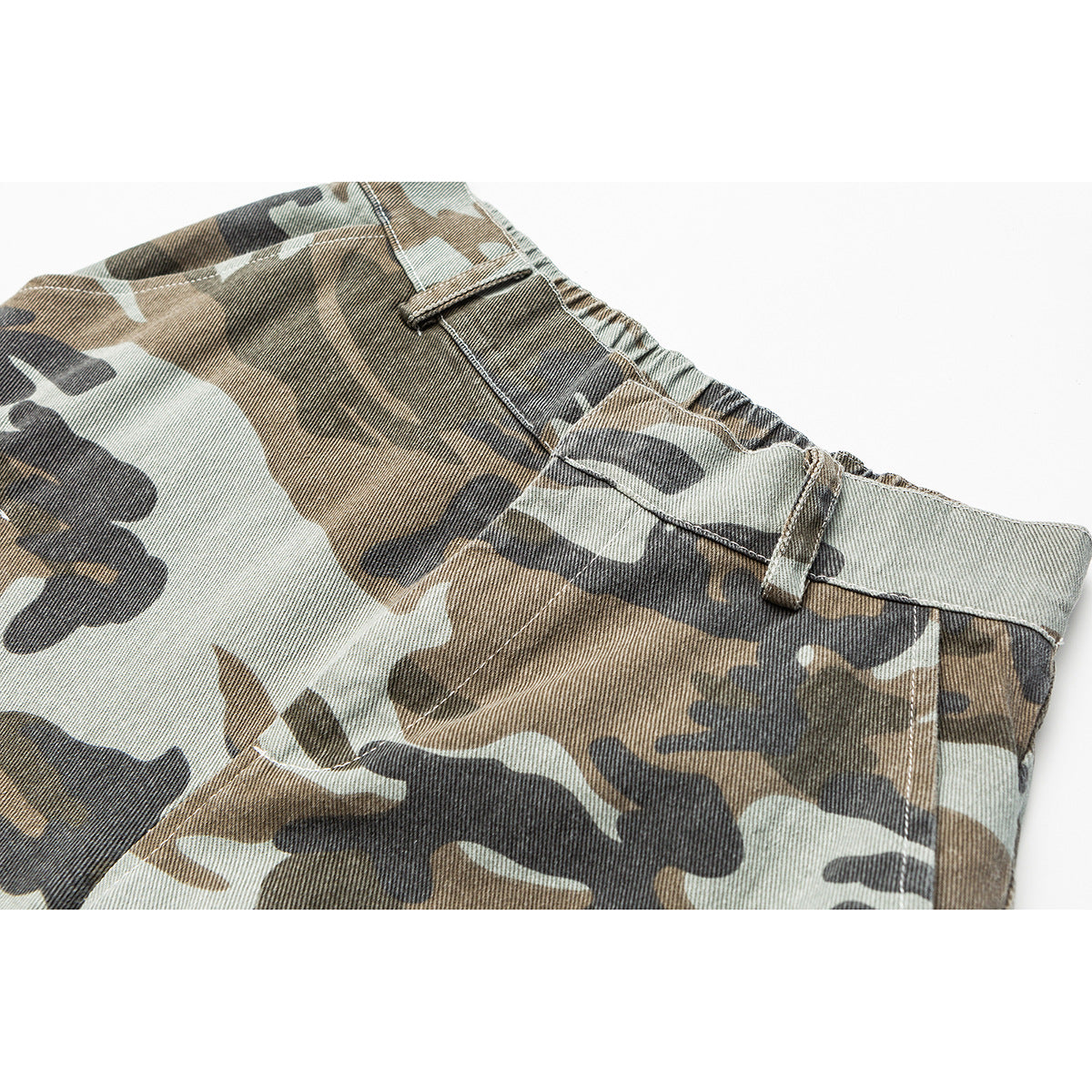 Close-up of camouflage trousers showing the elastic waistband, belt loop and upper front panel.