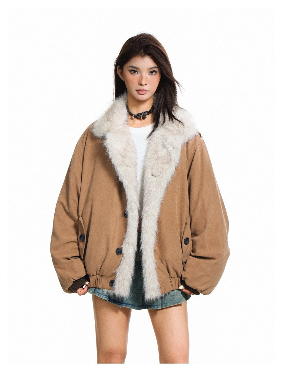 Model wearing a taupe jacket with a wide cream fur collar and front trim over a white top and denim skirt.