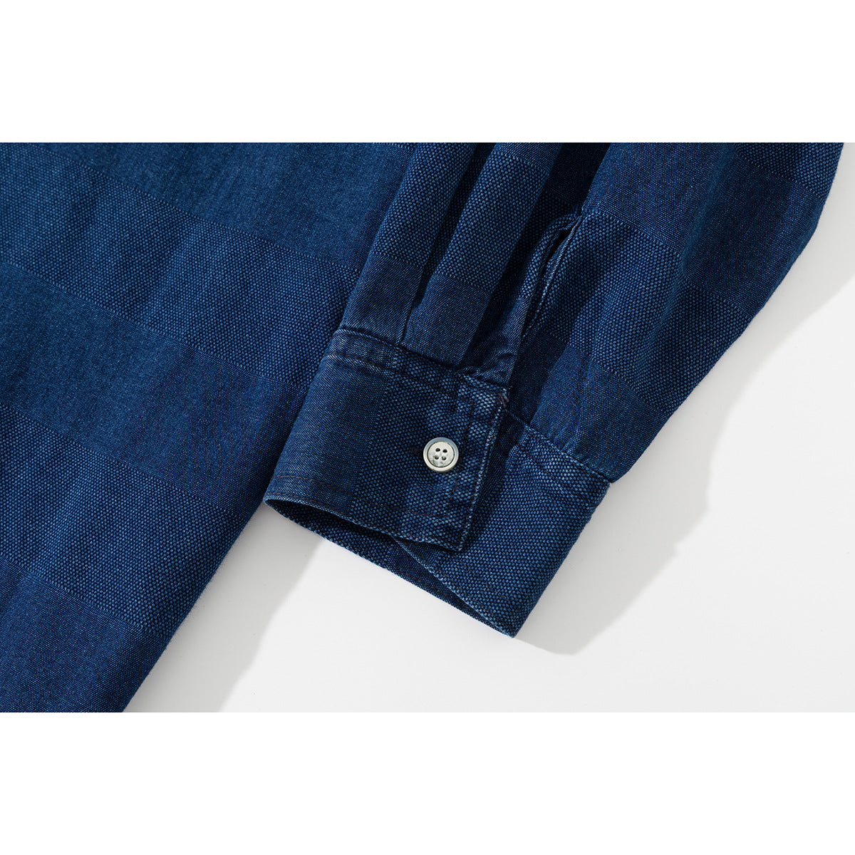 Close-up of the navy shirt's buttoned cuff and textured striped fabric.