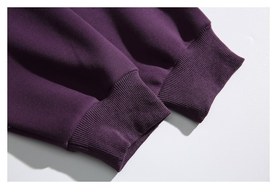 Close-up of two dark purple sweatshirt sleeves with ribbed cuffs.