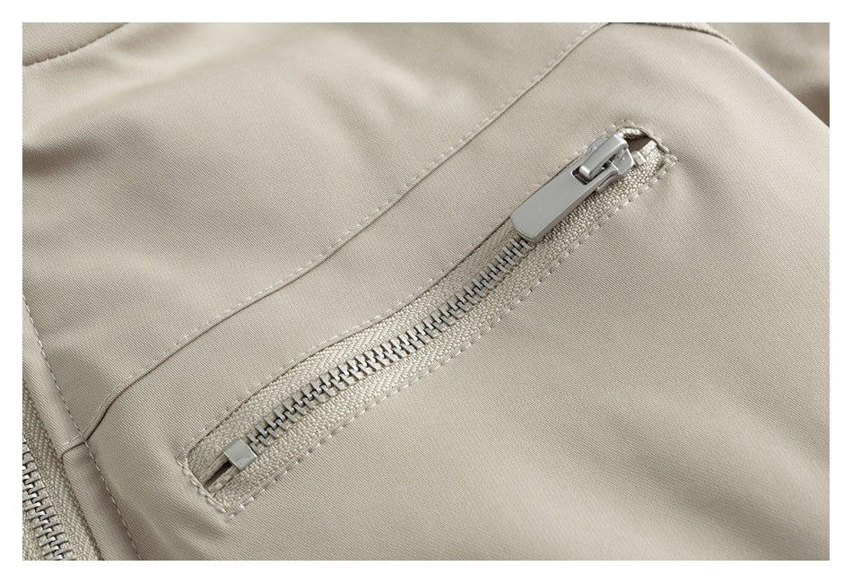 Close-up of a beige jacket's diagonal zip pocket and stitched seams.