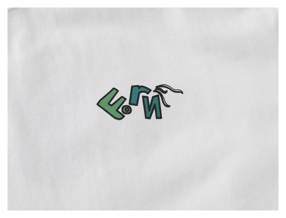 Close-up of a small green and teal graphic logo printed on white T-shirt fabric.