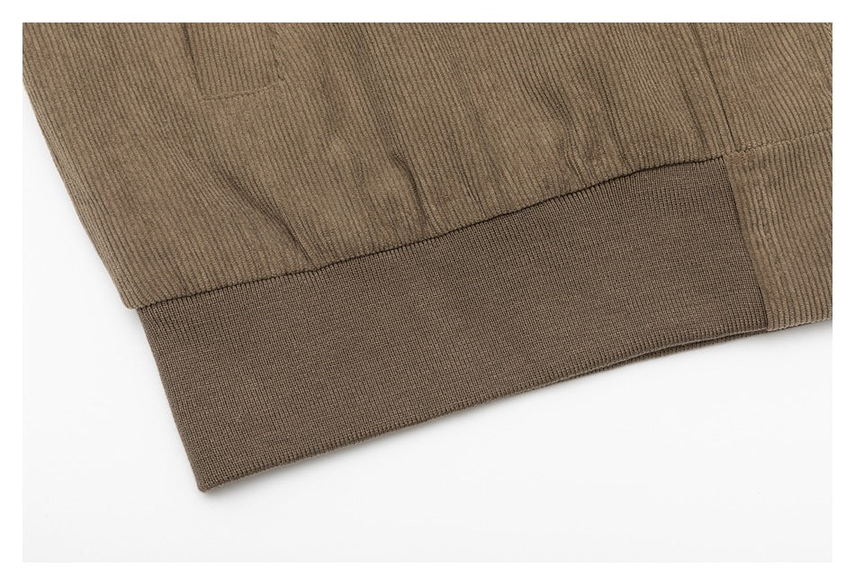 Close-up of a taupe jacket's gathered lower edge and wide ribbed hem band.