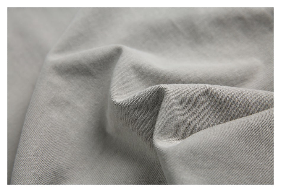 Close-up of the softly folded, plain light gray fabric and its knit texture.