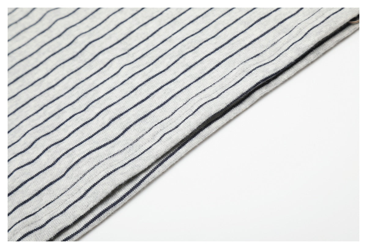 Close-up of a light gray garment with thin navy stripes and a diagonal stitched edge.