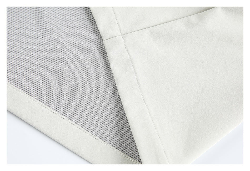 Close-up of an ivory garment with a gray perforated mesh inset bordered by stitched fabric.