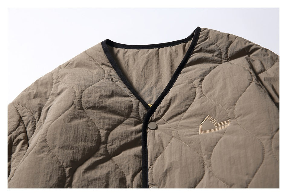 Close-up of the taupe jacket's V-neck, black binding, snap closure, and small embroidered mountain outline.