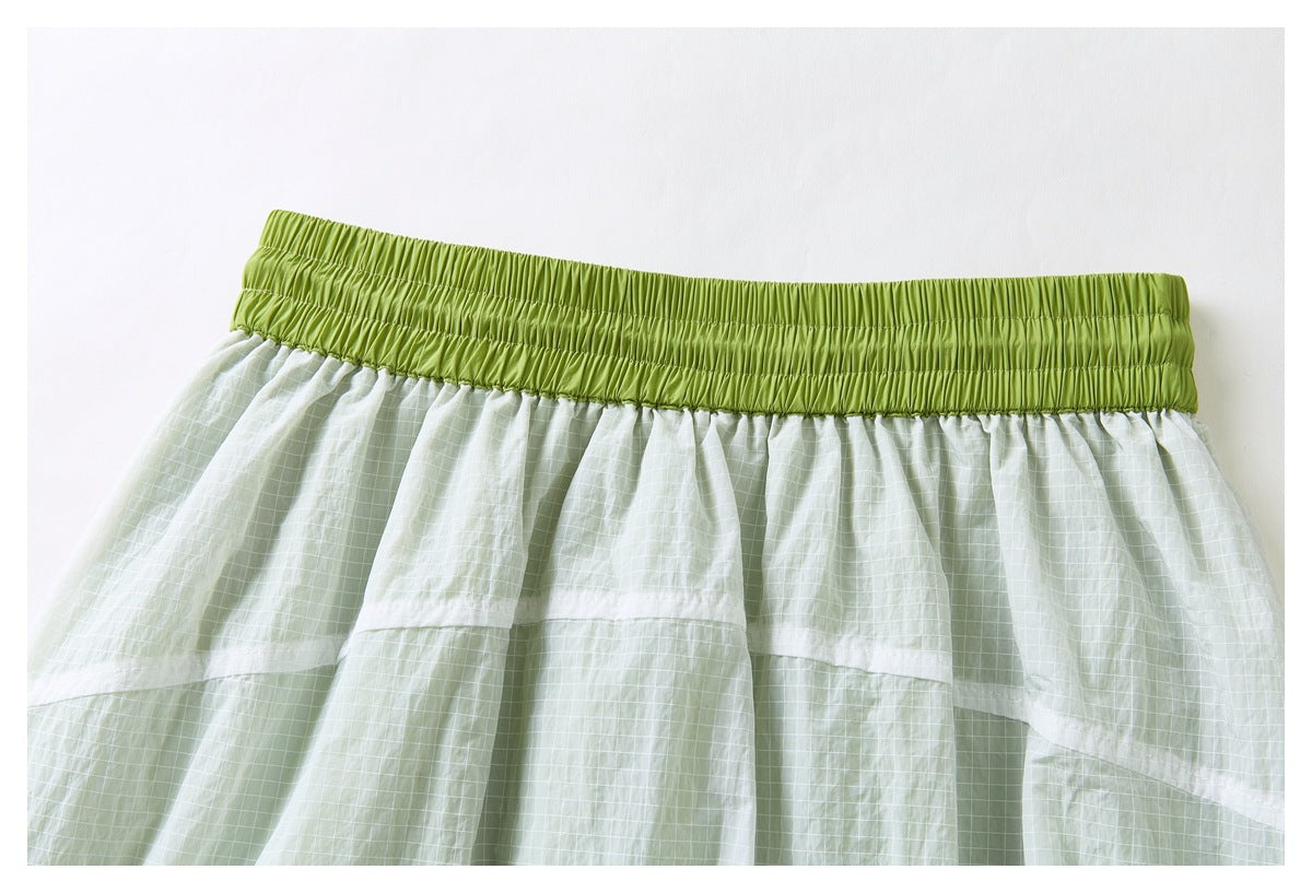 Front view of a pale green grid-patterned skirt with a wide lime-green elastic waistband and layered panels.