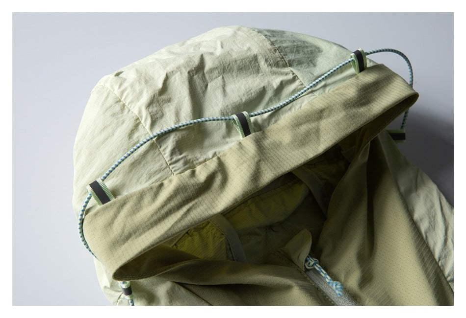 Close-up of a pale sage jacket hood with a blue-and-white drawcord and toggle details.
