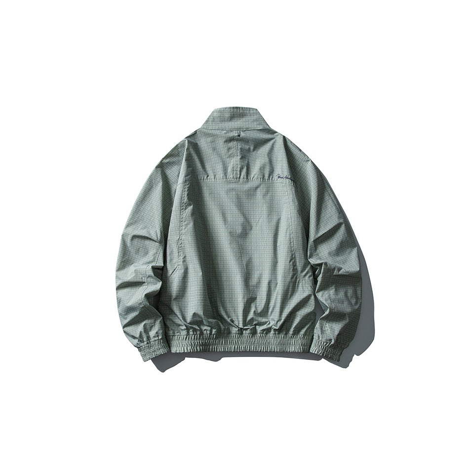 Back view of a pale sage-green jacket with a fine check pattern, stand collar, gathered cuffs, and elasticated hem.