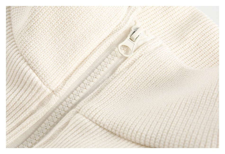 Close-up of a white zipper with a round pull on the jacket's textured knit collar.