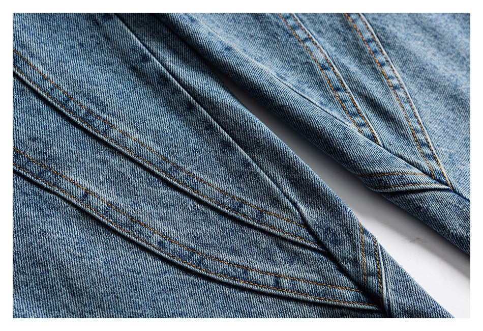 Close-up of light blue denim legs with intersecting panel seams and contrasting topstitching.