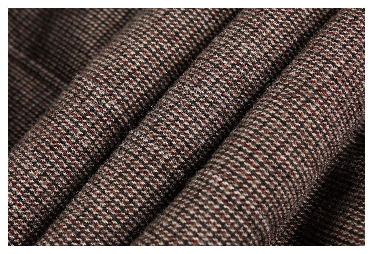 Close-up of folded brown, cream, and rust tweed fabric showing its textured weave.