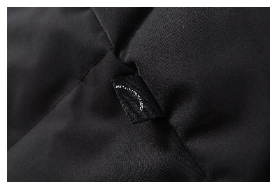 Close-up of a small woven brand label sewn into black garment fabric.