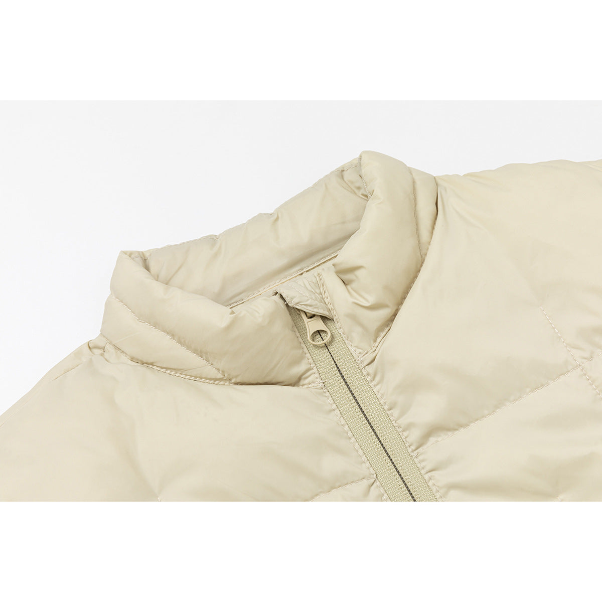 Close-up of a light beige quilted jacket's stand collar and front zipper.
