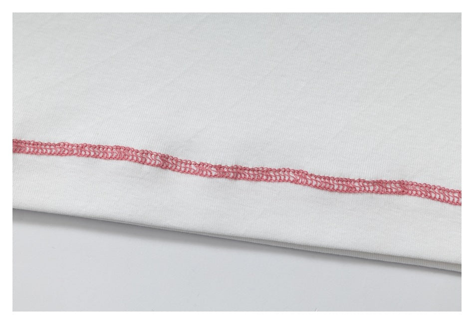 Close-up of white fabric with a pink overlock seam.