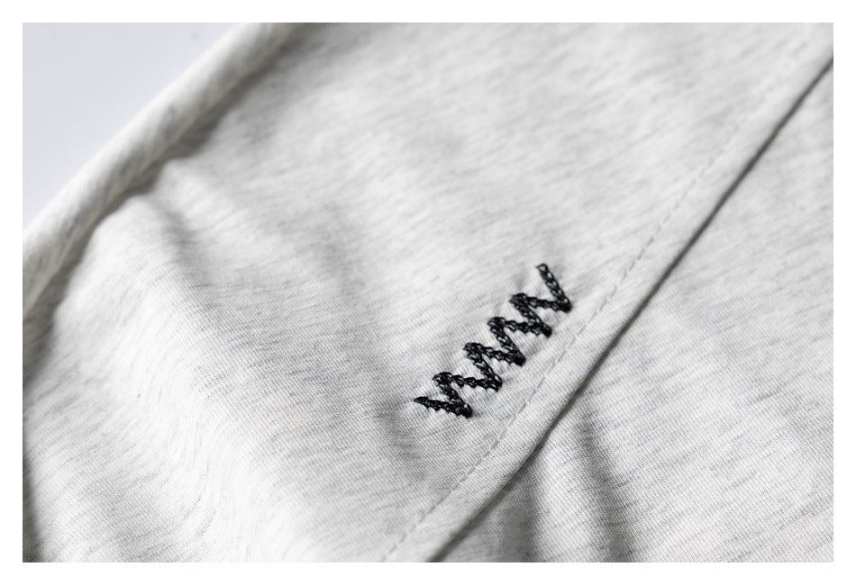 Close-up of black embroidered lettering on light gray marl fabric.
