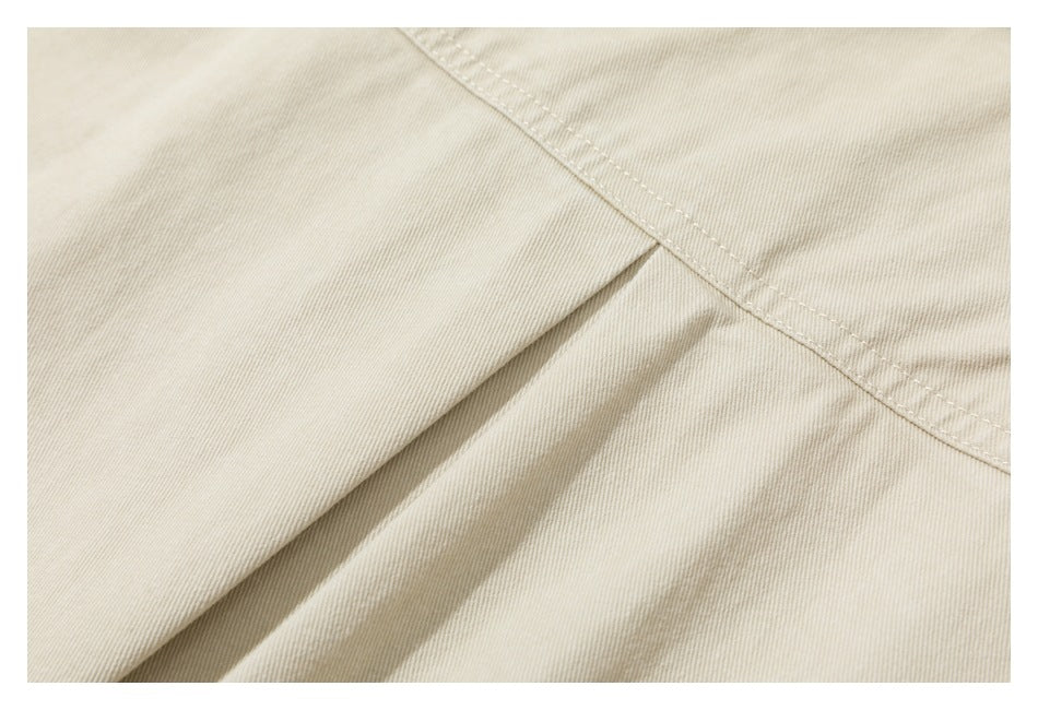 Close-up of an ivory garment seam and overlapping fabric panels.