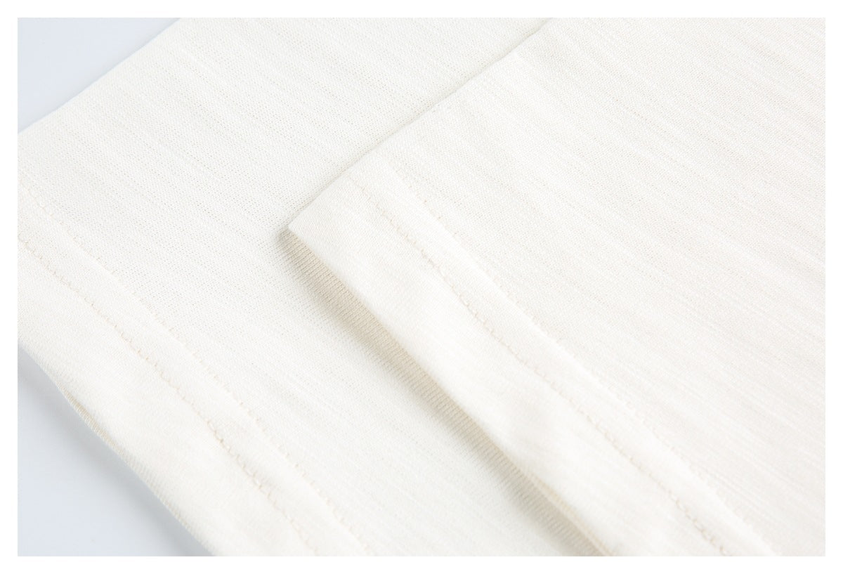 Close-up of off-white knit garment with a folded seam and visible stitching.