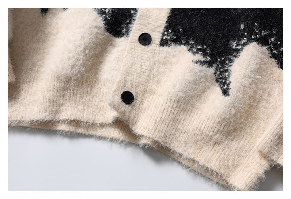 Close-up of black buttons on the ivory placket, with the cardigan's fuzzy black-and-ivory pattern and ribbed hem.