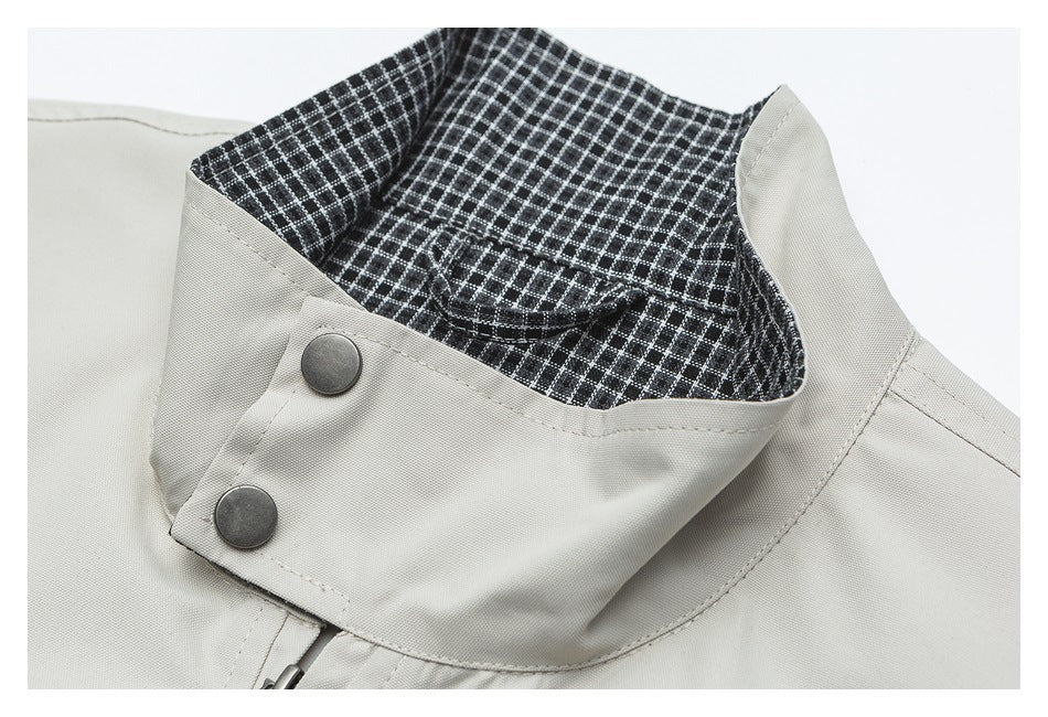 Close-up of a light gray jacket collar with dark checked lining and two snap buttons.