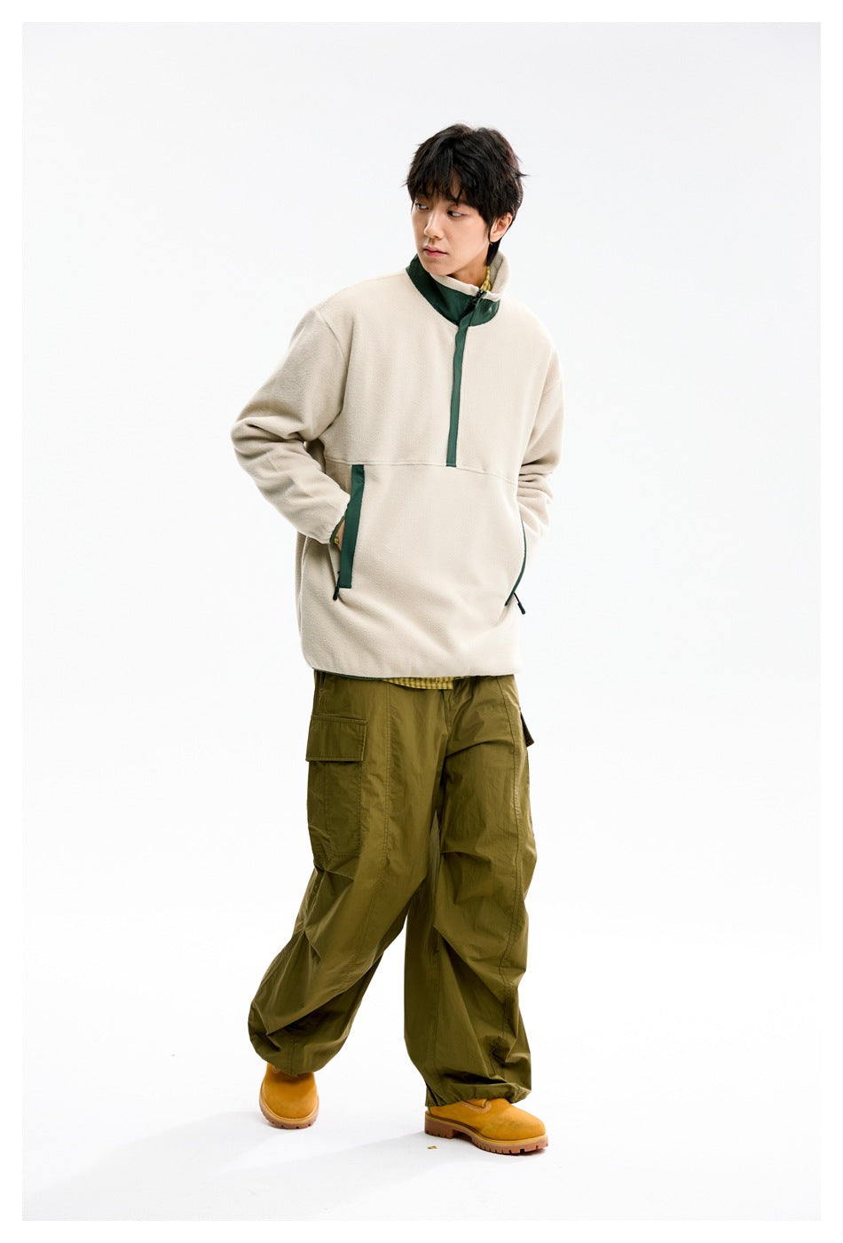 Model wearing a cream pullover with a raised dark green collar and trim, paired with olive cargo pants.
