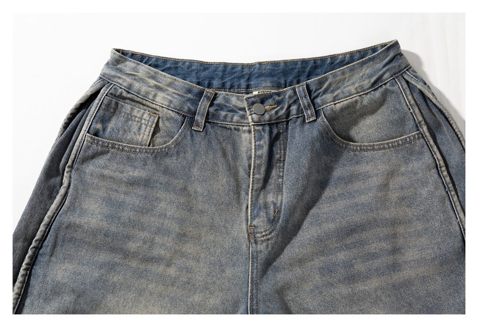 Close-up of the front waistband, button, belt loops and pockets on washed gray-blue denim shorts.