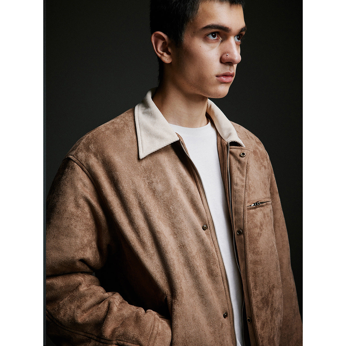 Close-up of a man wearing a tan jacket with a cream collar, front zipper, snap placket and zip chest pocket.