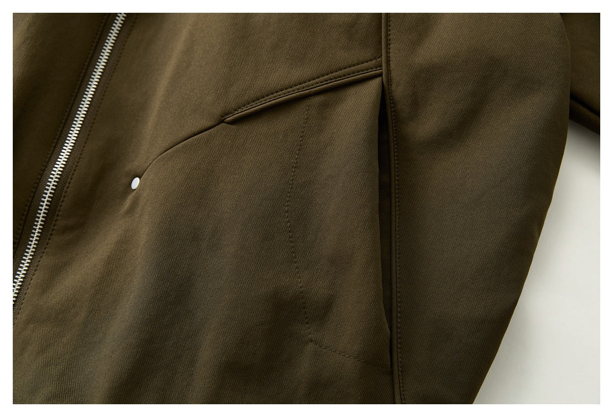 Close-up of an olive-brown jacket showing a slanted pocket opening, silver zipper, and sleeve seam.