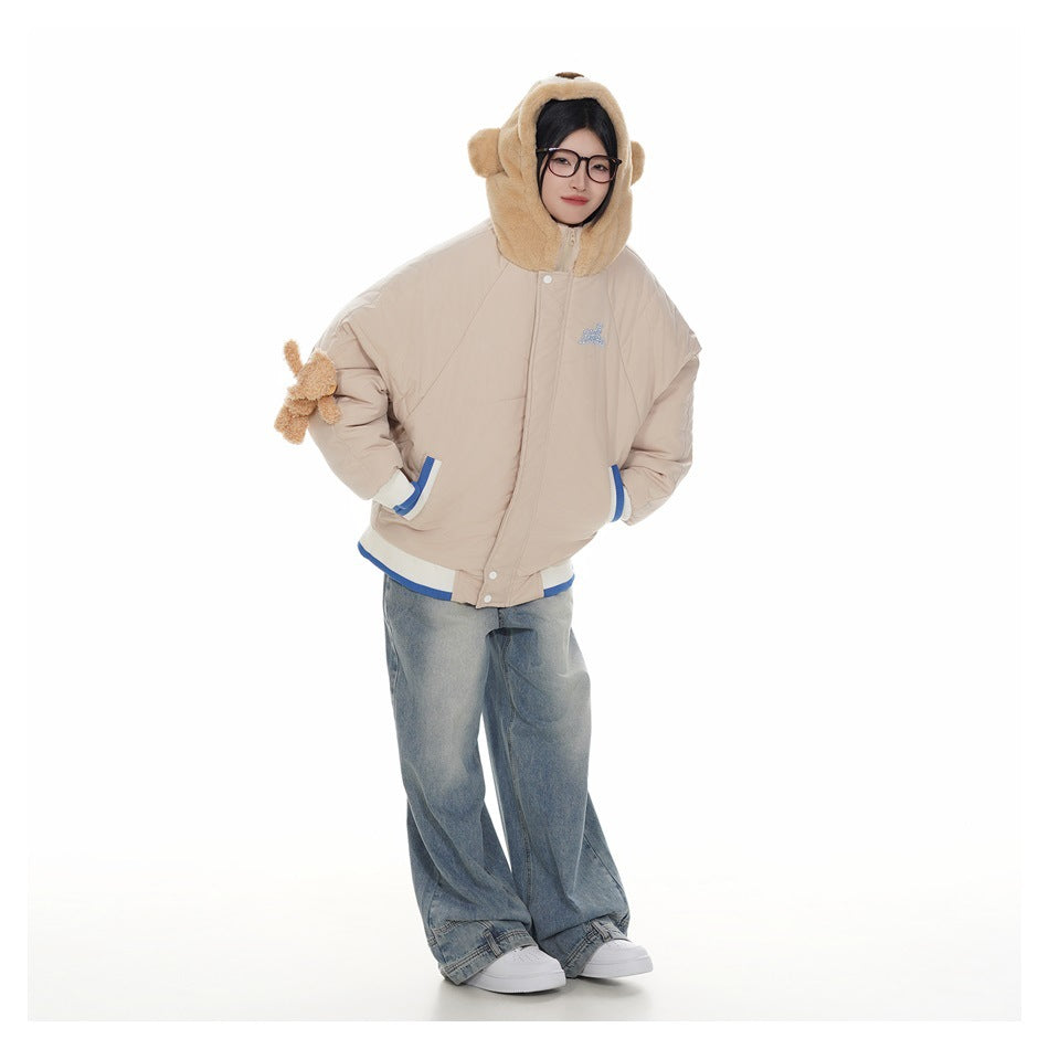 Full-length front view of a model wearing a beige bear-hood jacket with blue-and-white trim and loose jeans.