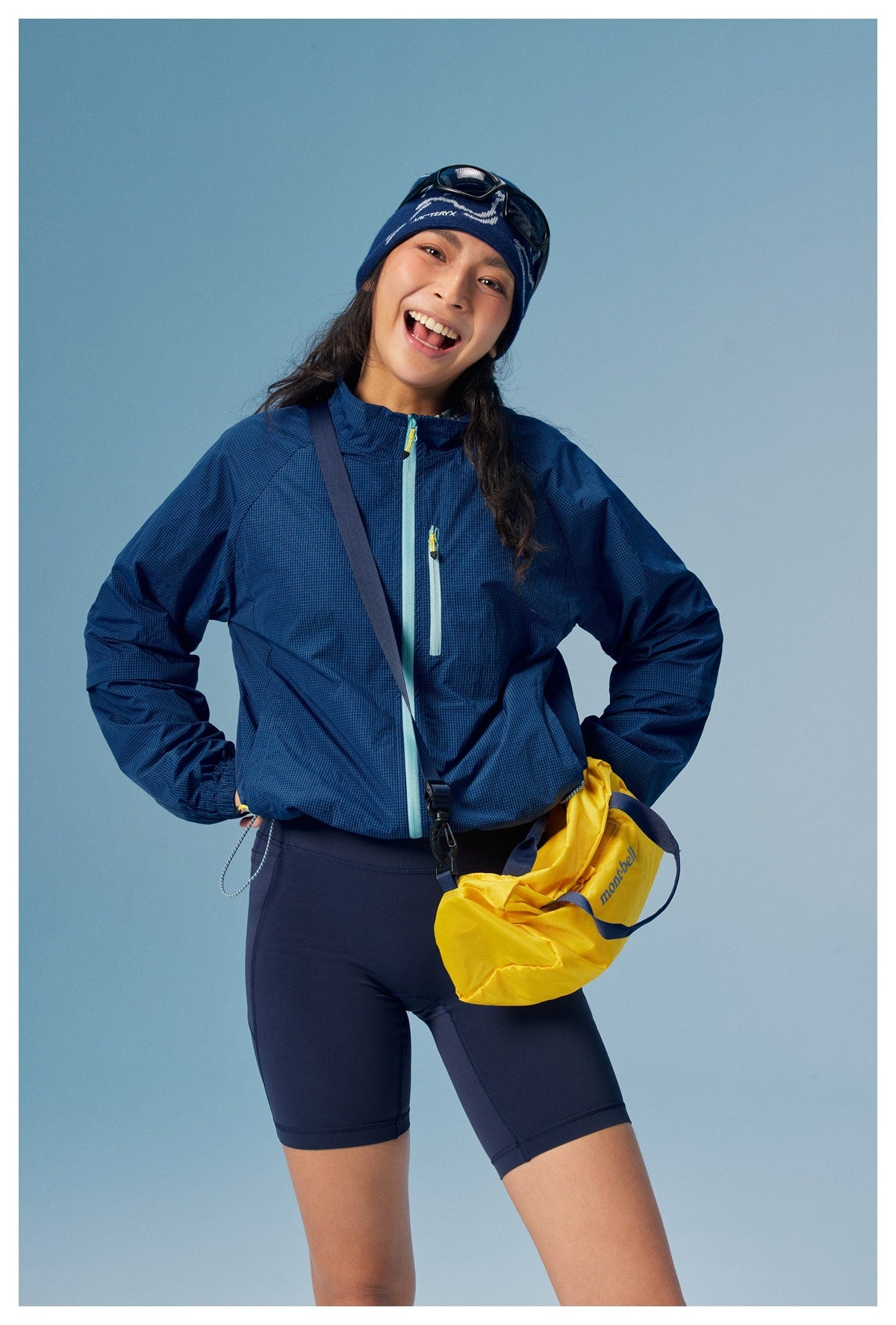 Close view of a model wearing a navy grid-pattern zip jacket with pale blue zippers and dark shorts.