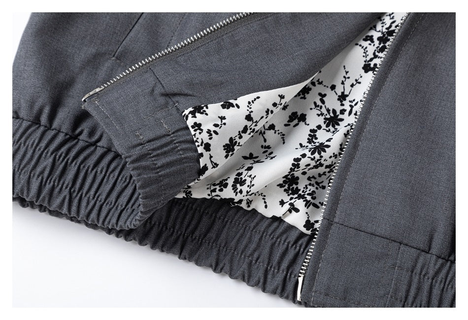 Close-up of a charcoal gray garment's gathered waistband, zipper, and black floral-print lining.