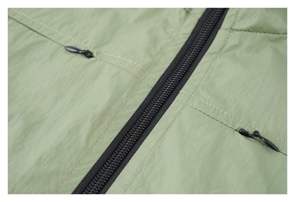 Close-up of the sage green jacket’s black center zipper and two small horizontal zip pockets.