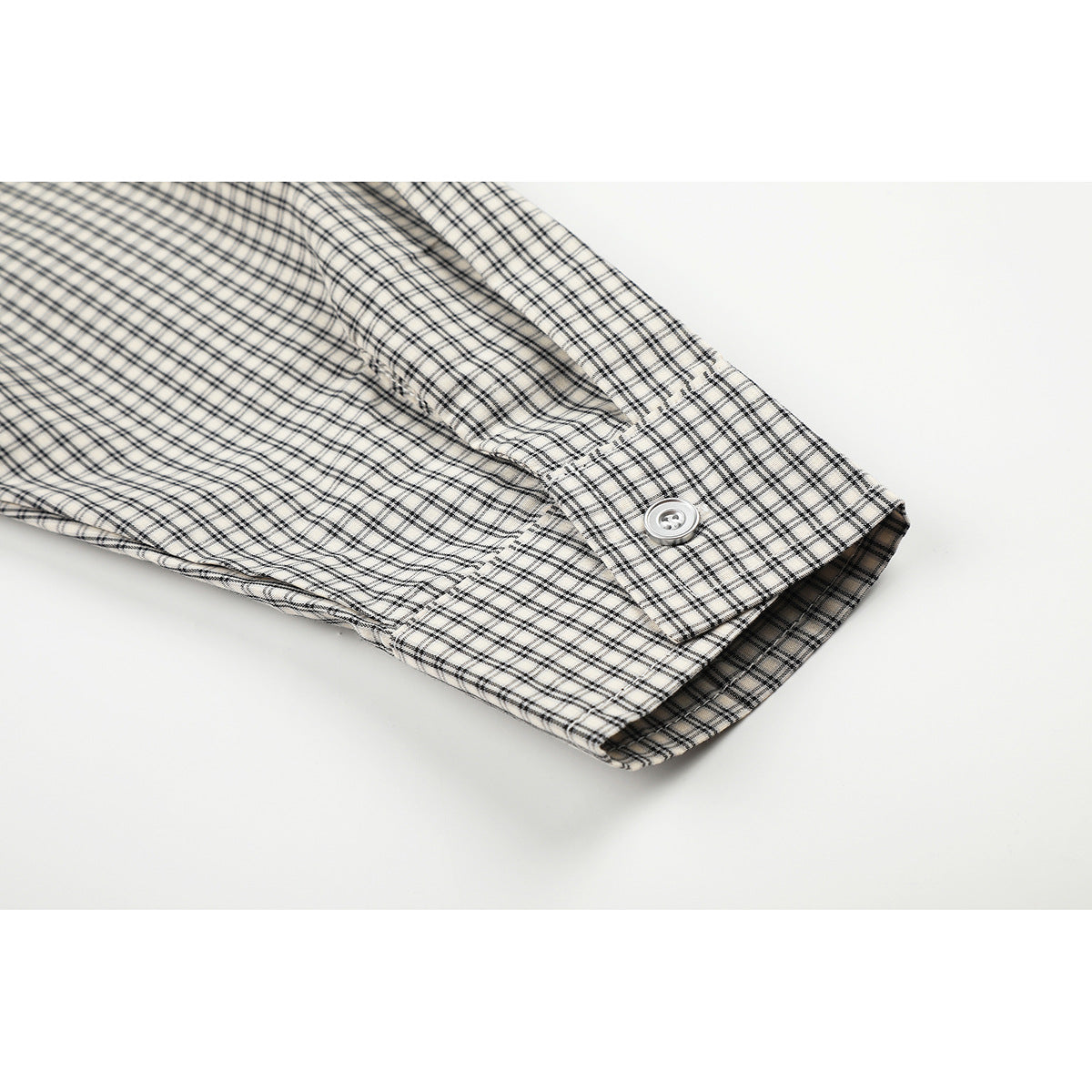 Close-up of the checked shirt sleeve cuff, showing a white button and stitched seam.