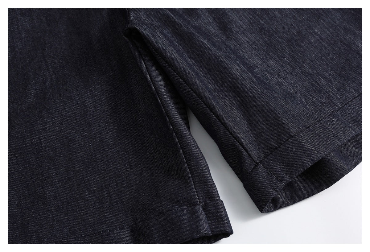 Close-up of dark indigo trousers showing the stitched hem and folded leg opening.